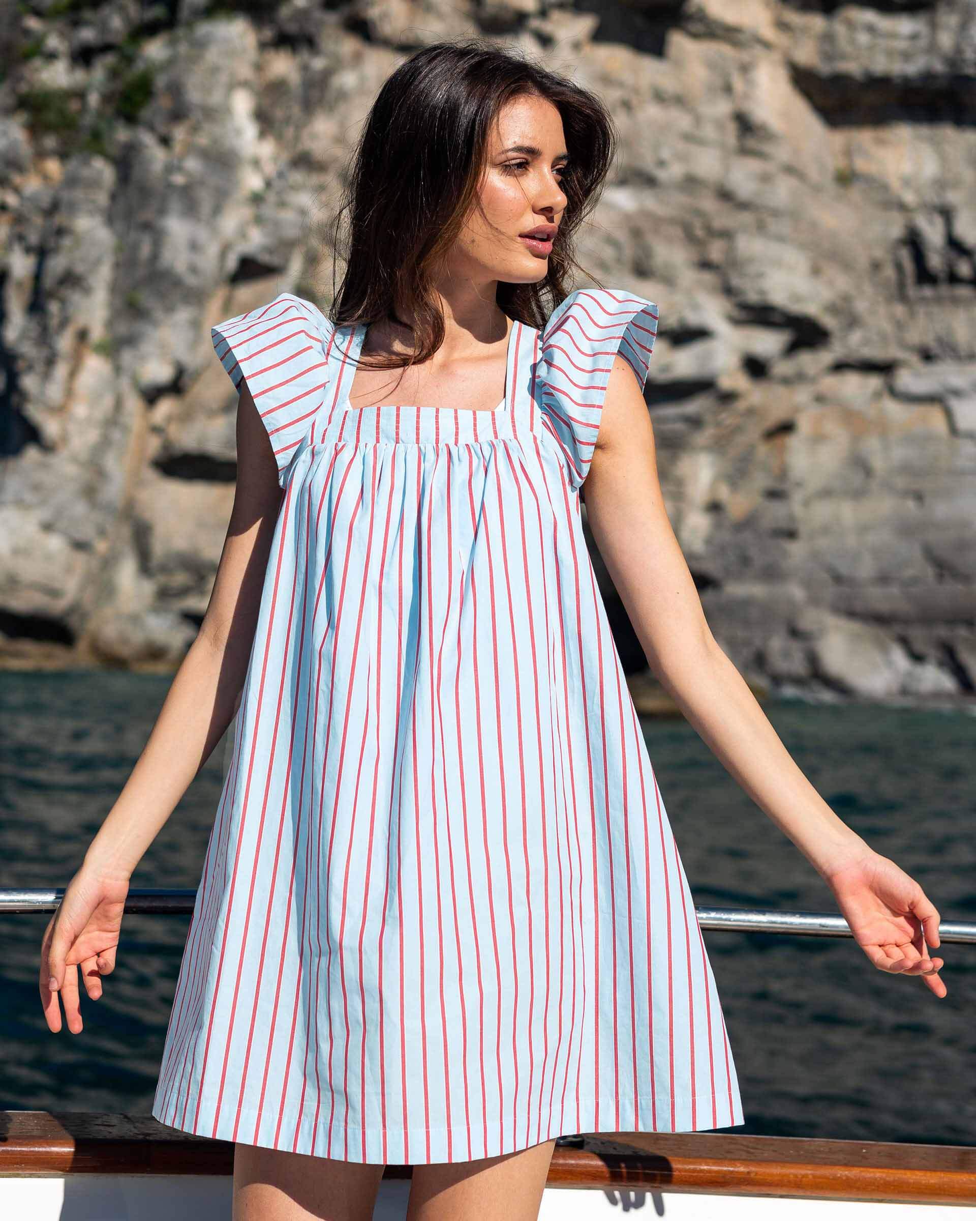 female wearing blue dress with red stripes sitting on a boat in Italy