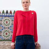Chili red ruffled cardigan knit with ribbed detailing and a decorative brooch.