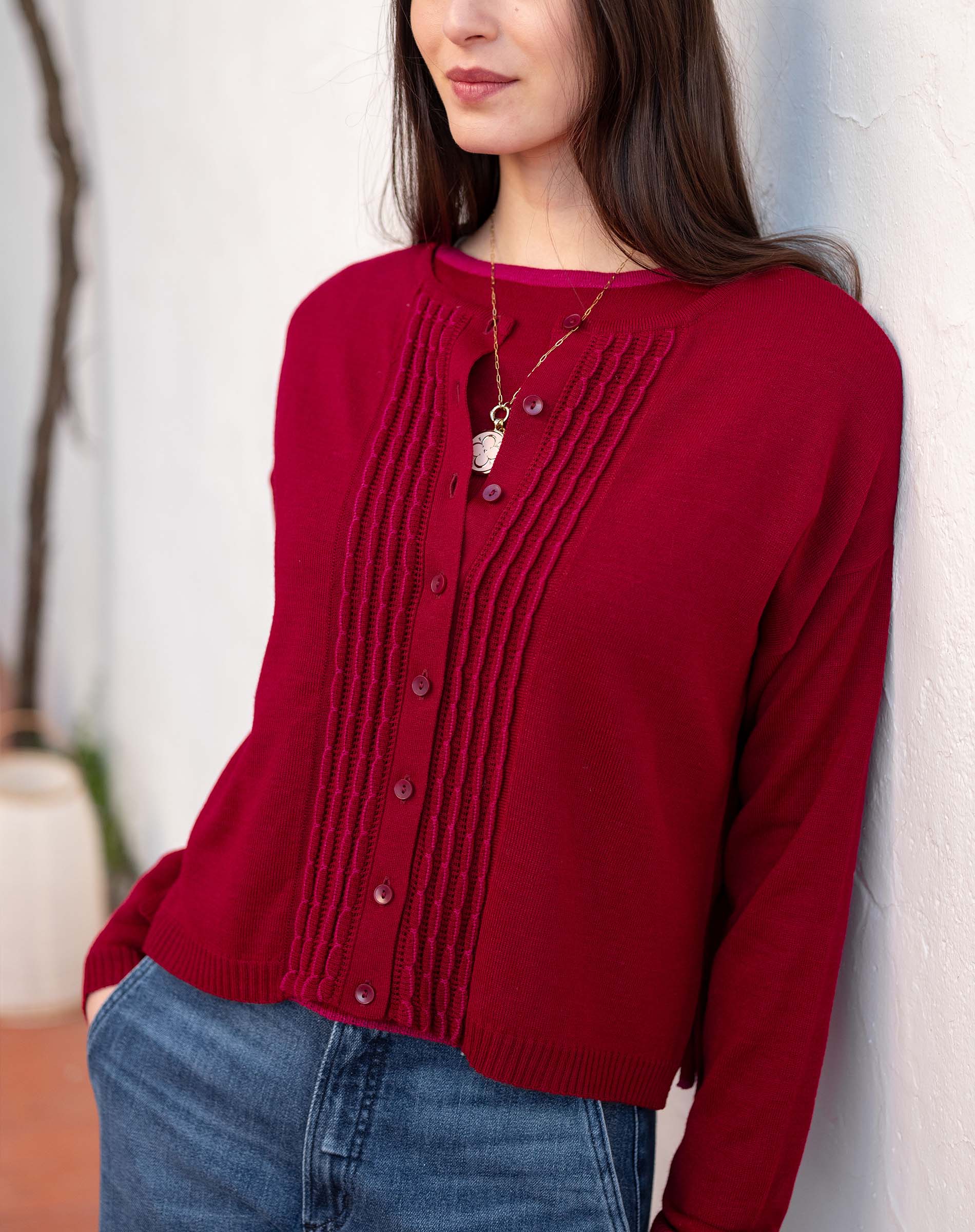 Wine red pleated knit cardigan featuring a buttoned front and textured vertical ribbing.