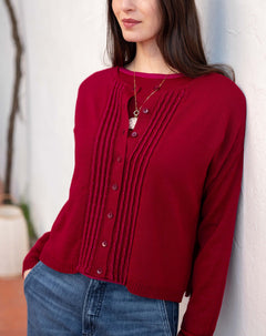 Wine red pleated knit cardigan featuring a buttoned front and textured vertical ribbing.