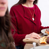 Wine red ribbed knit cardigan with a ruffled overlay and button details.