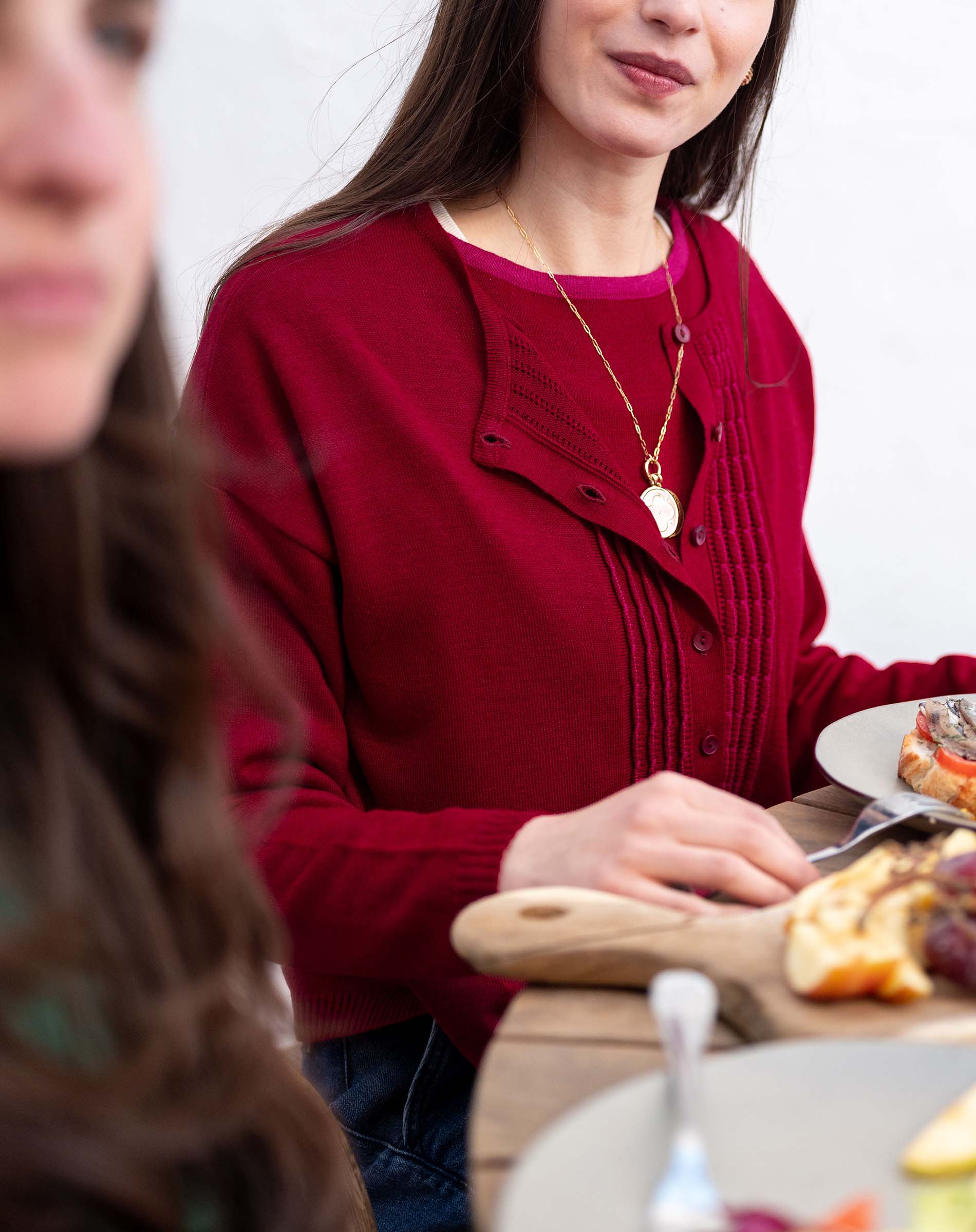 Wine red ribbed knit cardigan with a ruffled overlay and button details.