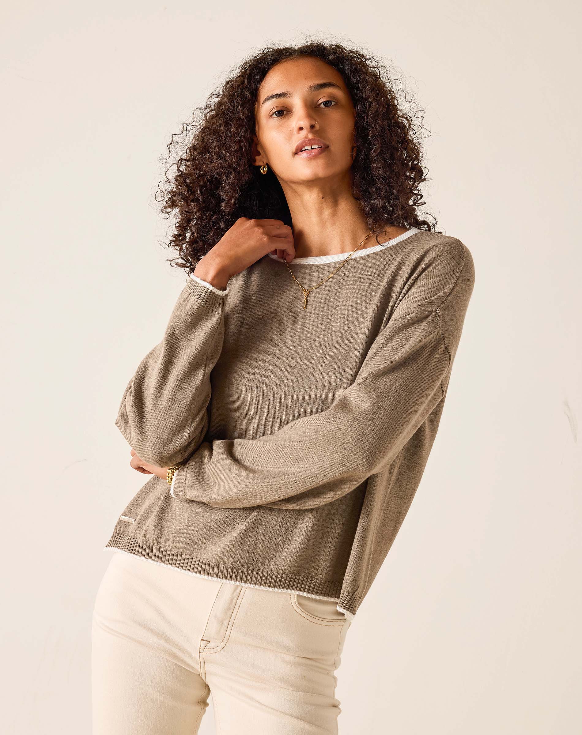 Woman wearing a brown sweater against a plain background