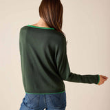 Back view of women's travel-friendly pine green knit sweater with a contrasting trim and blue denim jeans.