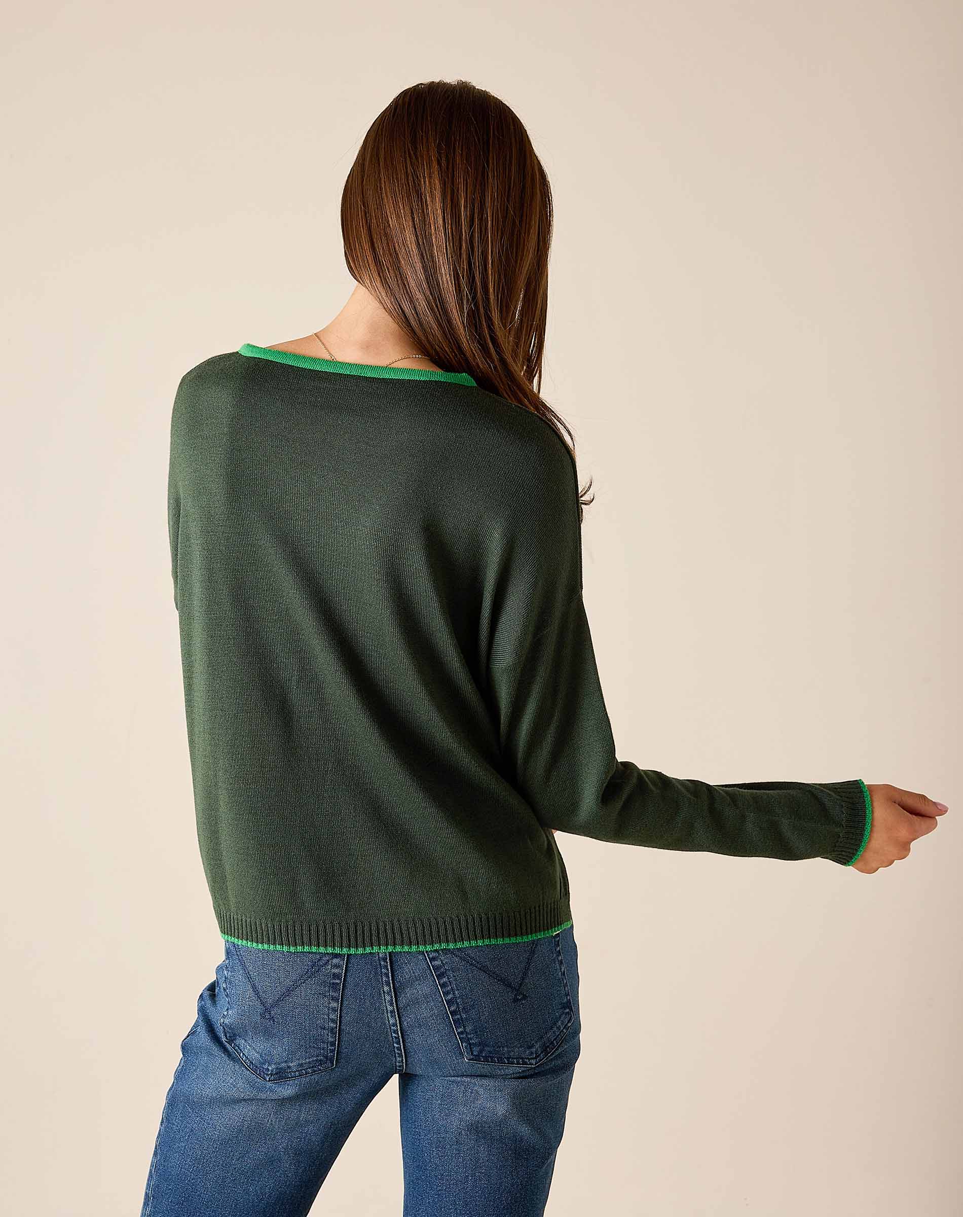 Back view of women's travel-friendly pine green knit sweater with a contrasting trim and blue denim jeans.