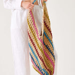 Person holding a colorful striped crochet bag against a white background