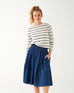 woman wearing Mersea carmel cashmere sweater in navy stripes standing with hand in pocket