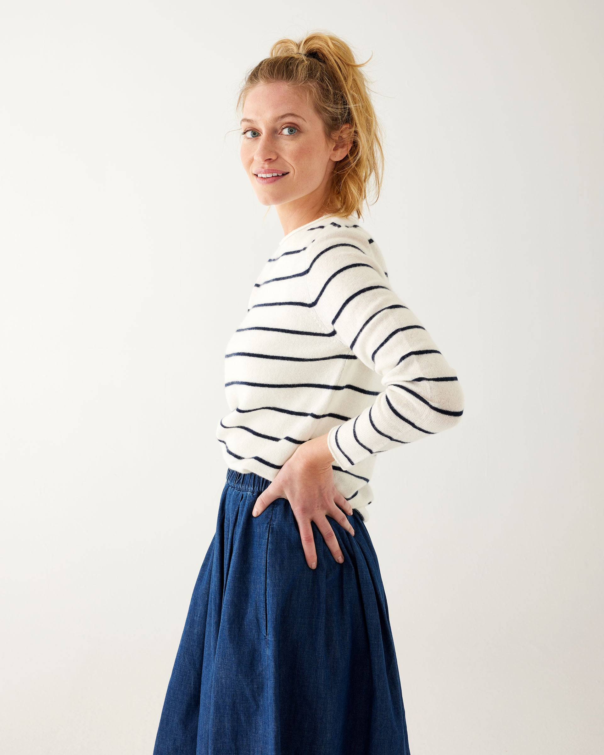 woman wearing Mersea carmel cashmere sweater in navy stripes standing with hands on hips