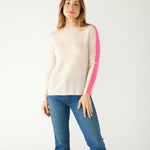 woman wearing mersea carmel cashmere sweater in champagne color with hot pink stripes down sleaves