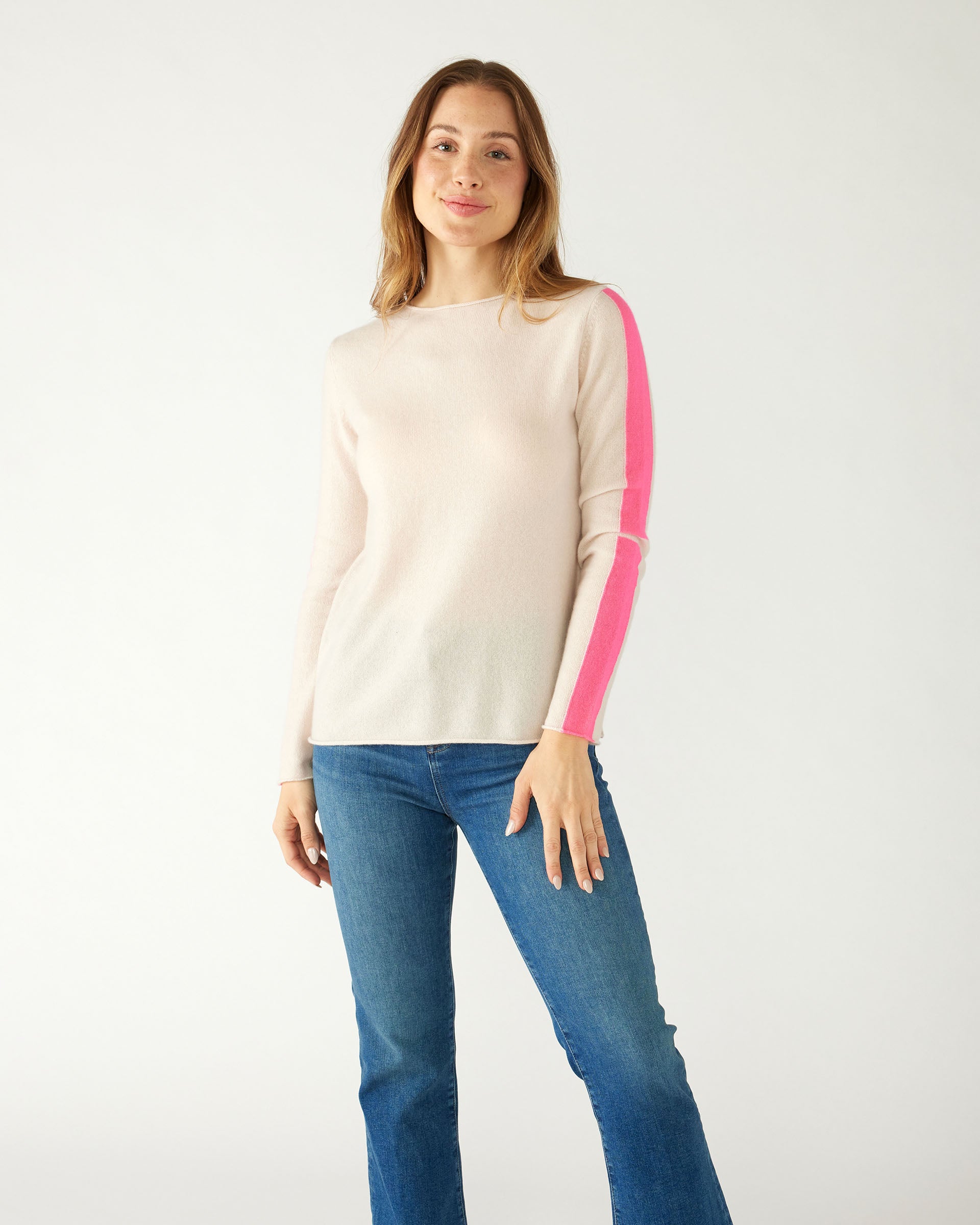 woman wearing mersea carmel cashmere sweater in champagne color with hot pink stripes down sleaves