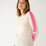 closeup of woman wearing mersea carmel cashmere sweater in champagne color with hot pink stripes down sleaves