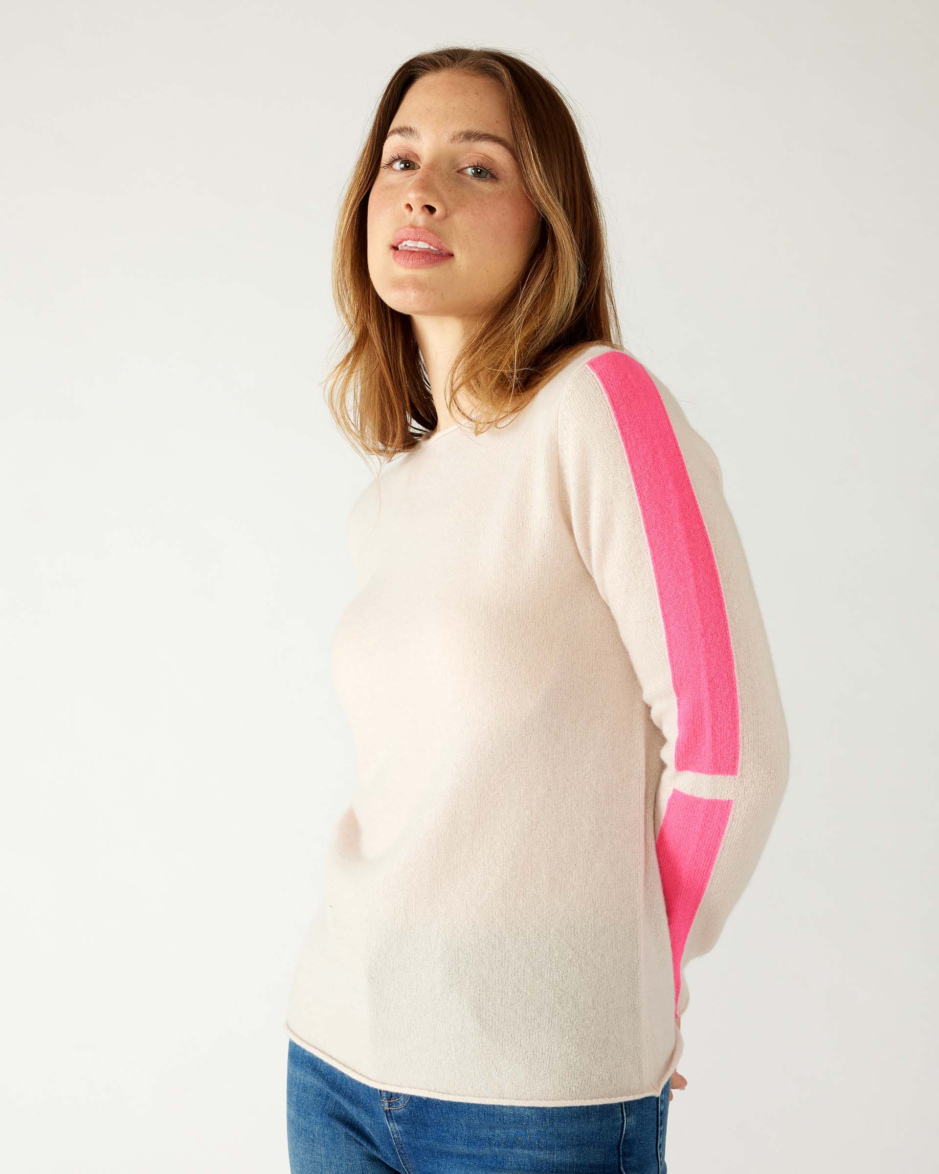 closeup of woman wearing mersea carmel cashmere sweater in champagne color with hot pink stripes down sleaves