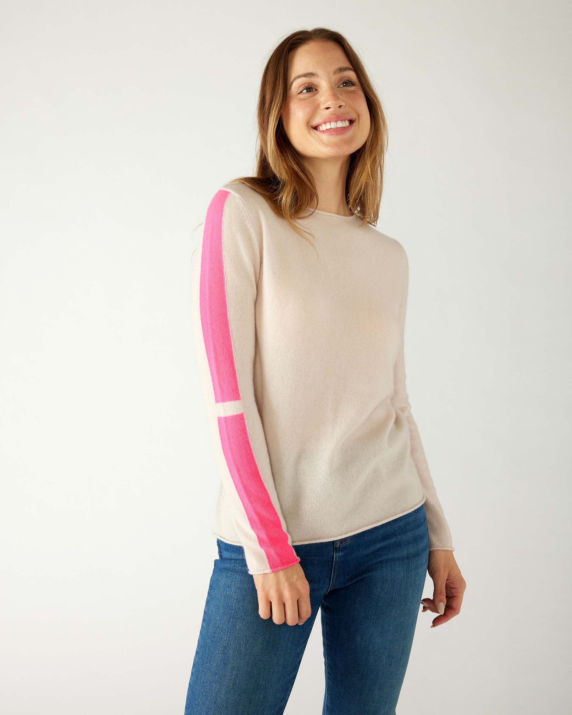 woman wearing mersea carmel cashmere sweater in champagne color with hot pink stripes down sleaves