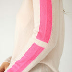 closeup of sleeve on woman wearing mersea carmel cashmere sweater in champagne color with hot pink stripes down sleaves