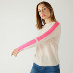 woman wearing mersea carmel cashmere sweater in champagne color with hot pink stripes down sleaves with arm out