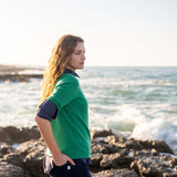 profile of woman wearing mersea carmel sweater in jade standing near water on rocks