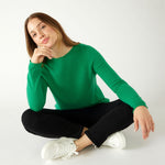 woman sitting crosslegged wearing mersea carmel sweater in jade