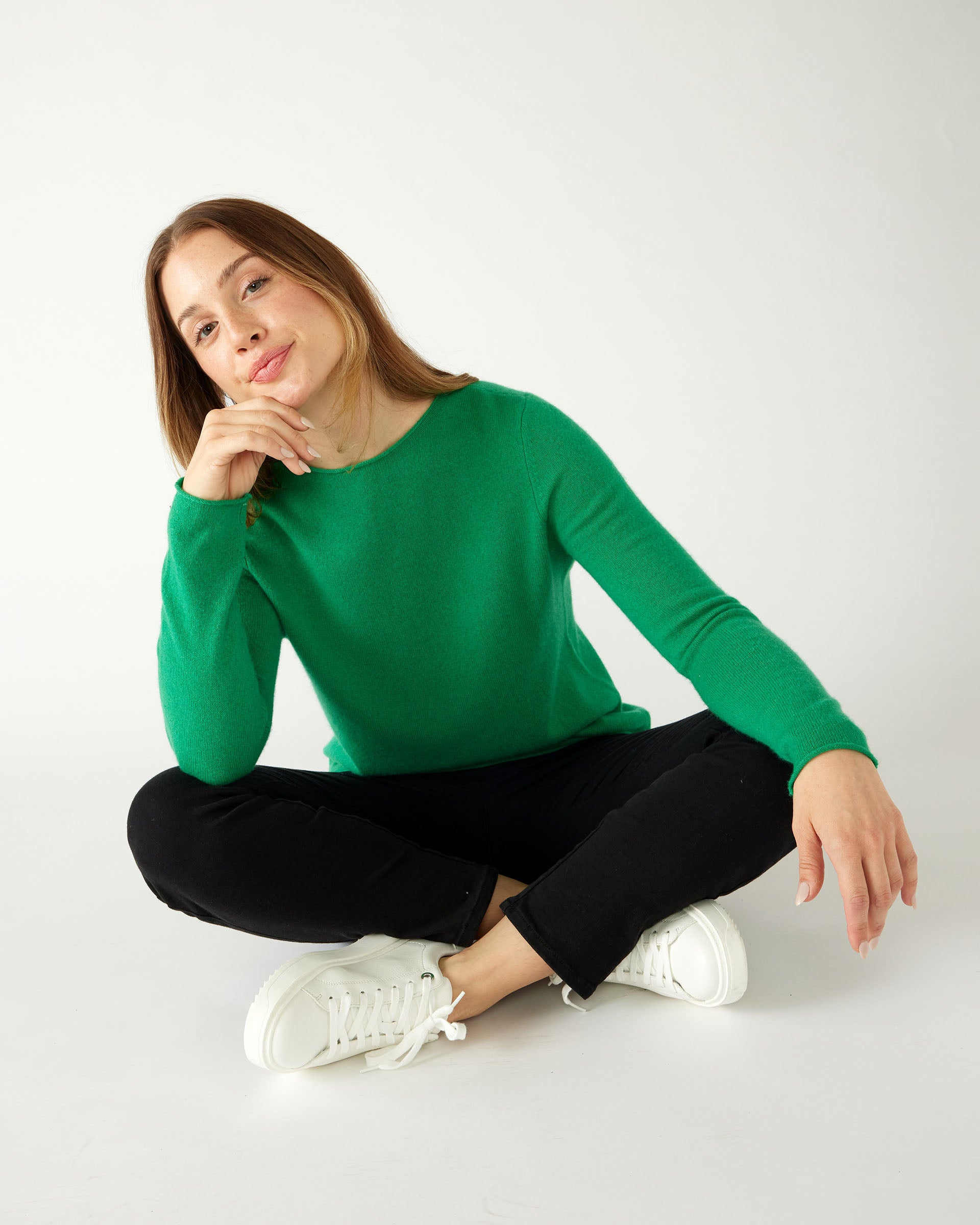woman sitting crosslegged wearing mersea carmel sweater in jade