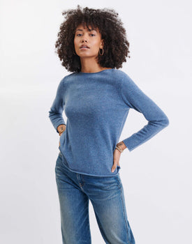female wearing blue cashmere sweater standing on a white background