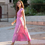 Woman in a pink dress walking outdoors on a sunny day.