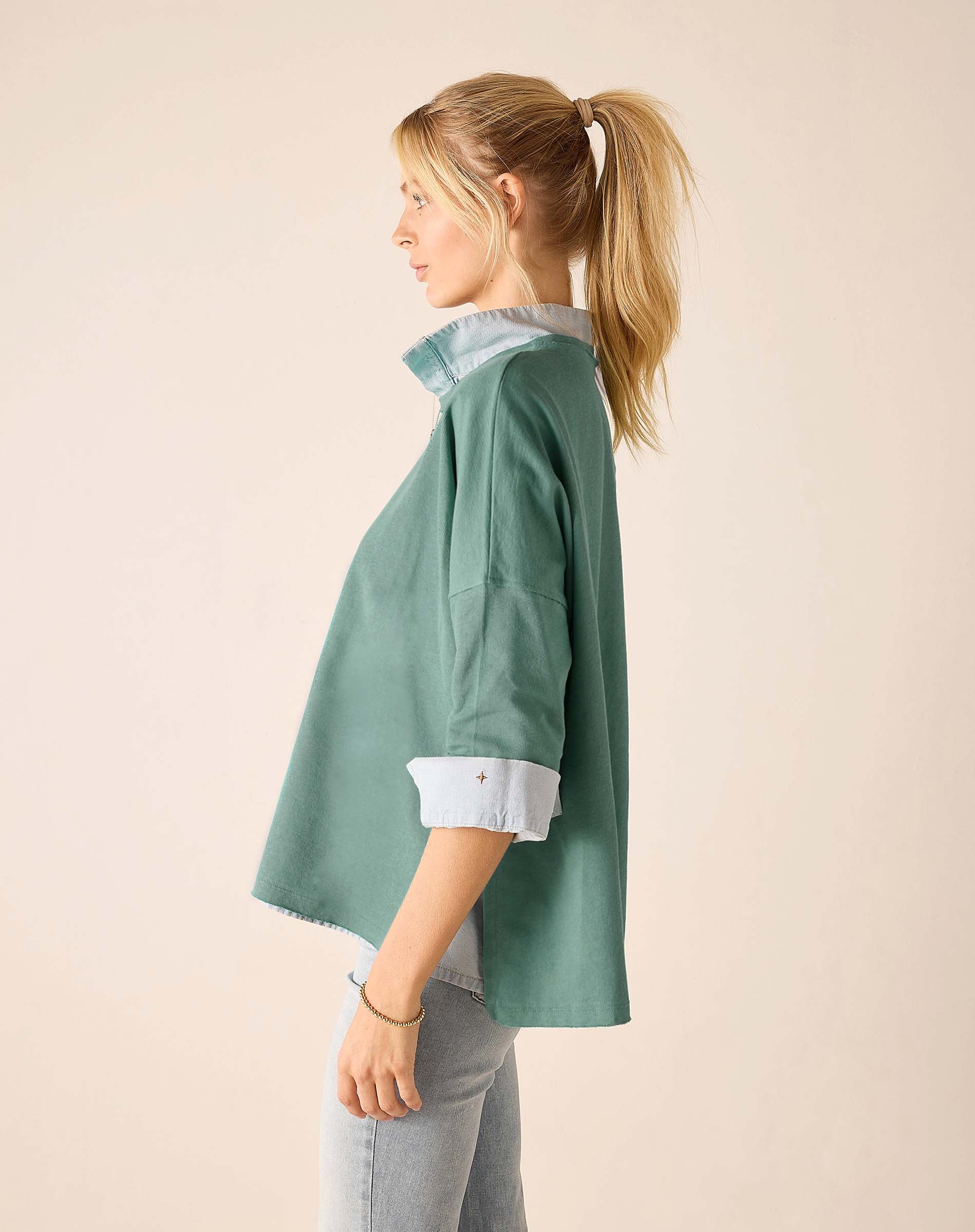 Woman wearing a green shirt with rolled-up sleeves on a beige background