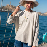 Woman on a boat wearing a wide-brimmed hat and casual outfit with a scenic background.