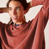 Woman wearing a rust-colored garment against a plain background