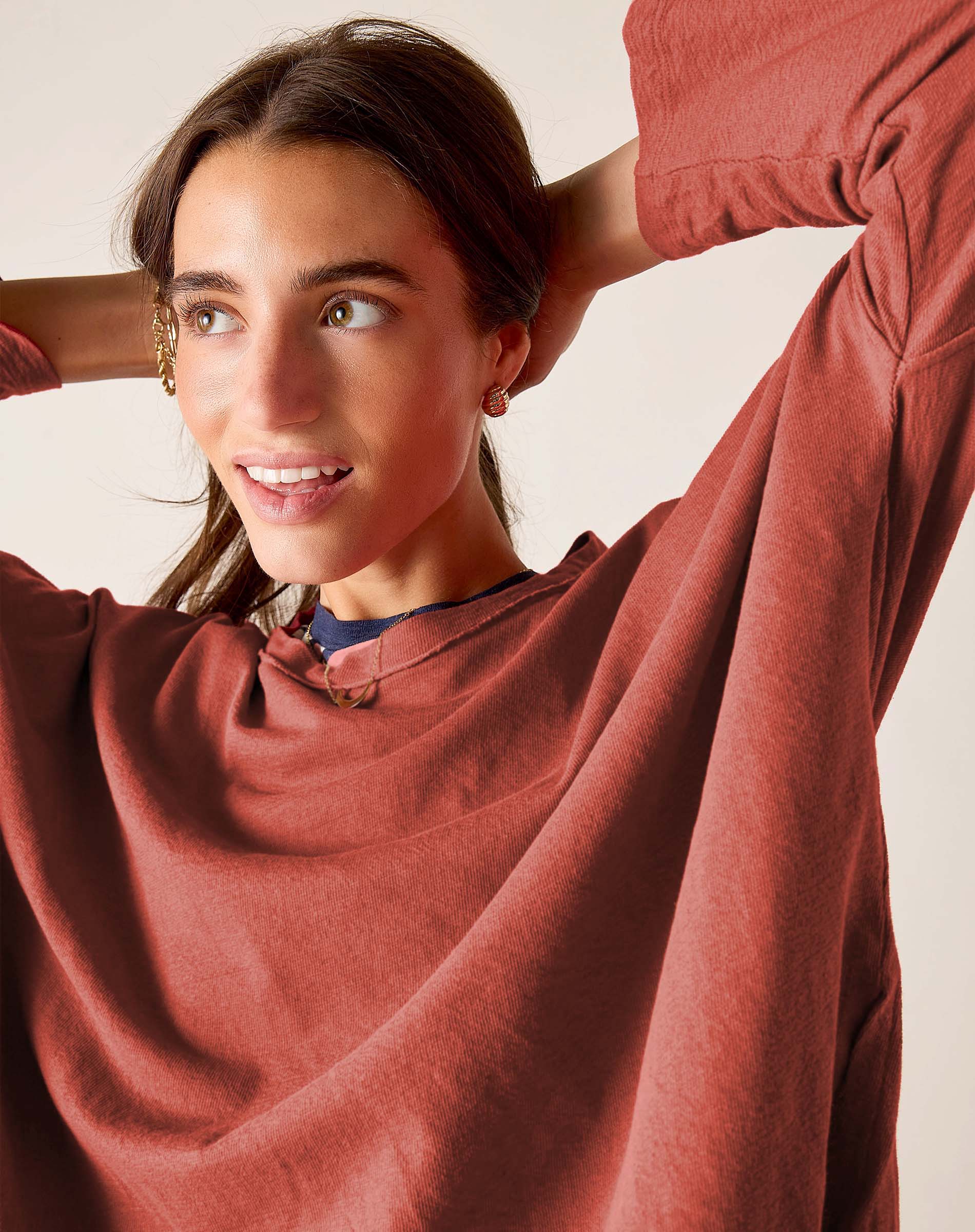 Woman wearing a rust-colored garment against a plain background
