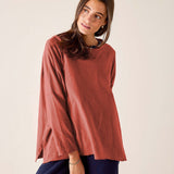 Woman wearing a rust-colored long-sleeve top against a plain background