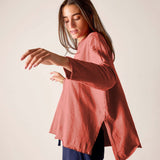 Woman wearing a pink blouse with long sleeves against a plain background
