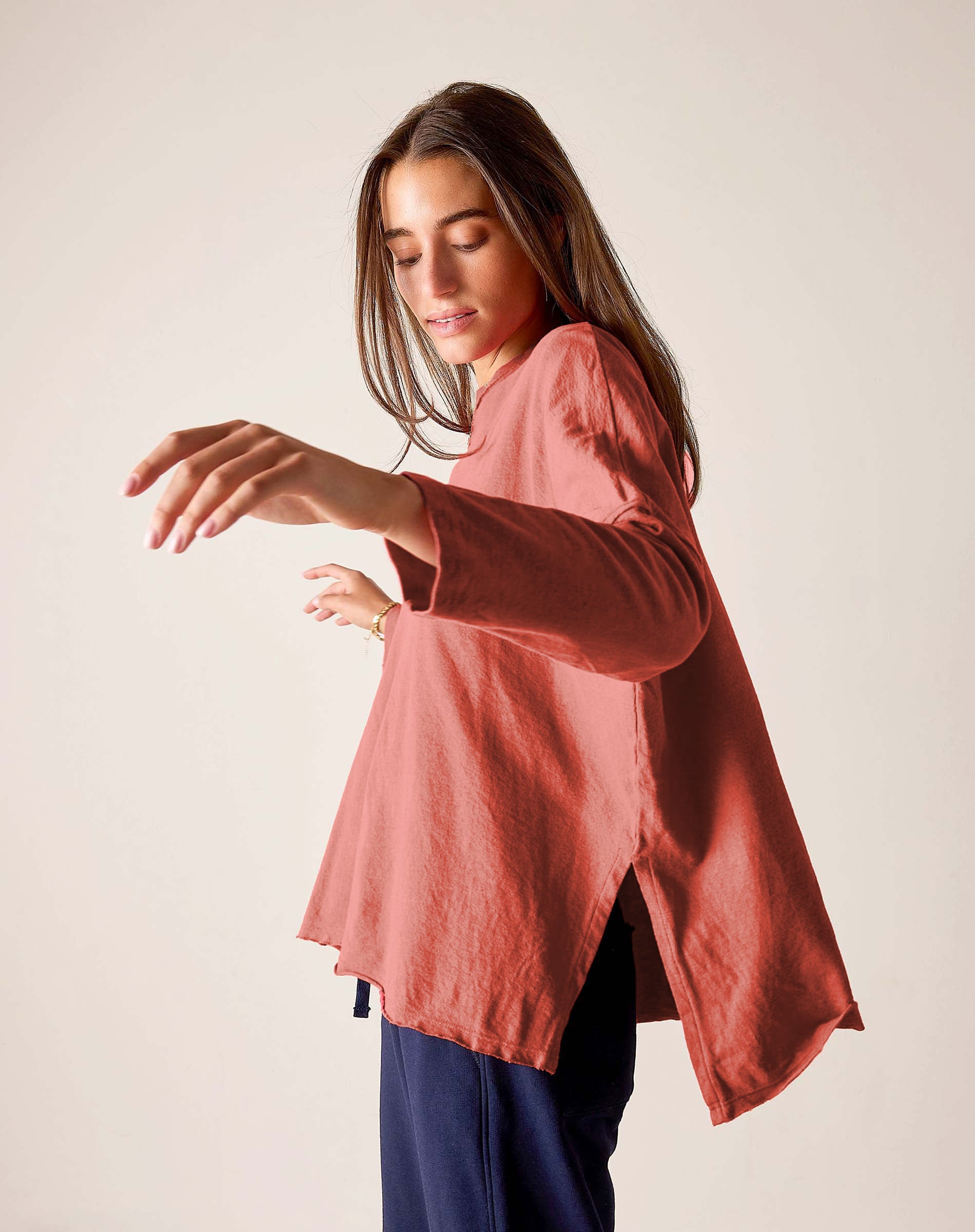 Woman wearing a pink blouse with long sleeves against a plain background