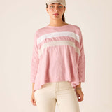 Woman wearing a pink long-sleeve top with white stripes and a beige cap on a plain background
