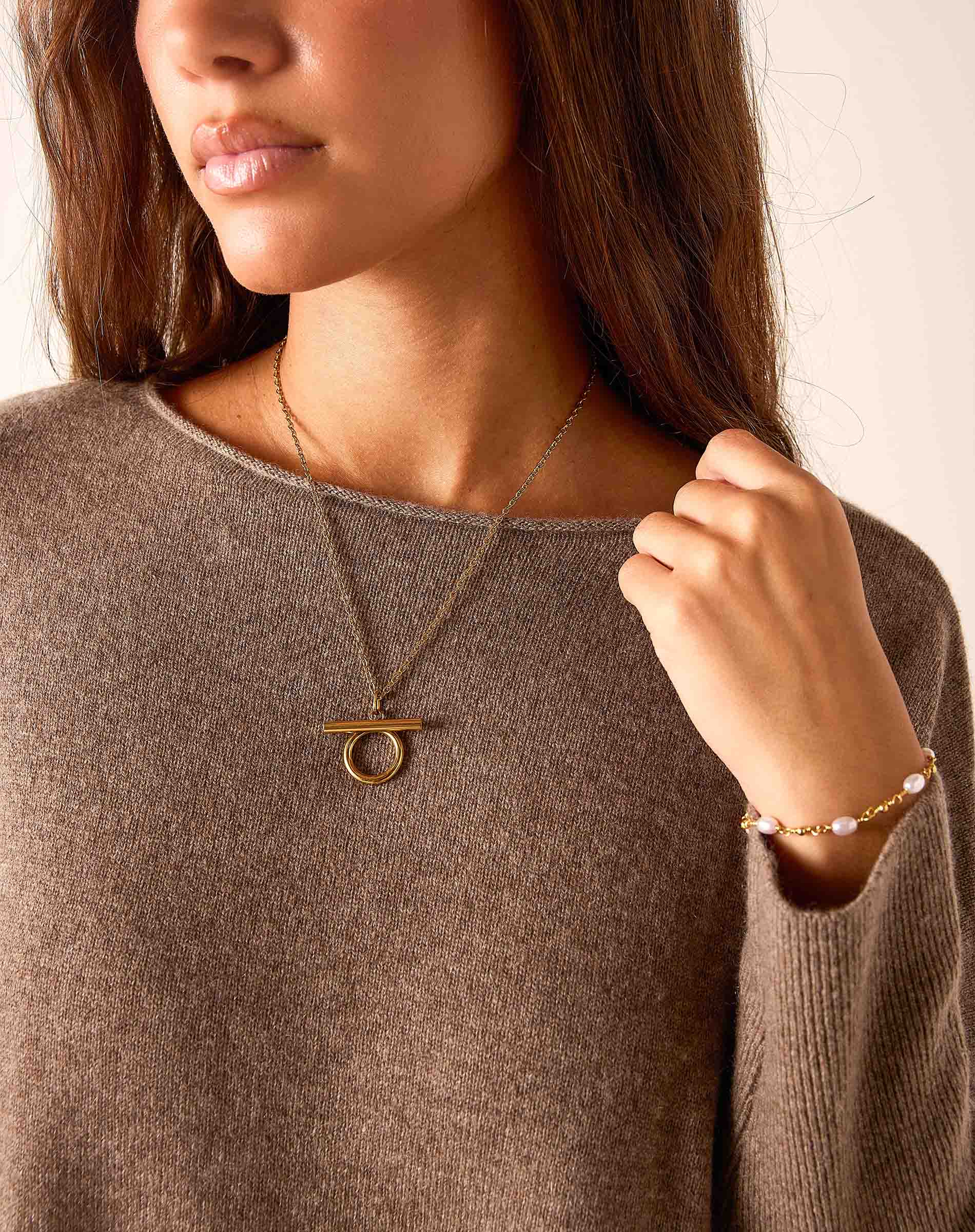 Cedar brown cashmere knit sweater with a round neckline and a layered gold-toned pendant necklace.