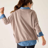 Back view of women's travel-friendly toast colored cashmere sweater with relaxed fit and layered denim shirt.