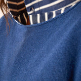Yale Blue cashmere knit sweater featuring a cozy knit weave and layered over a blue and white striped button-down shirt.