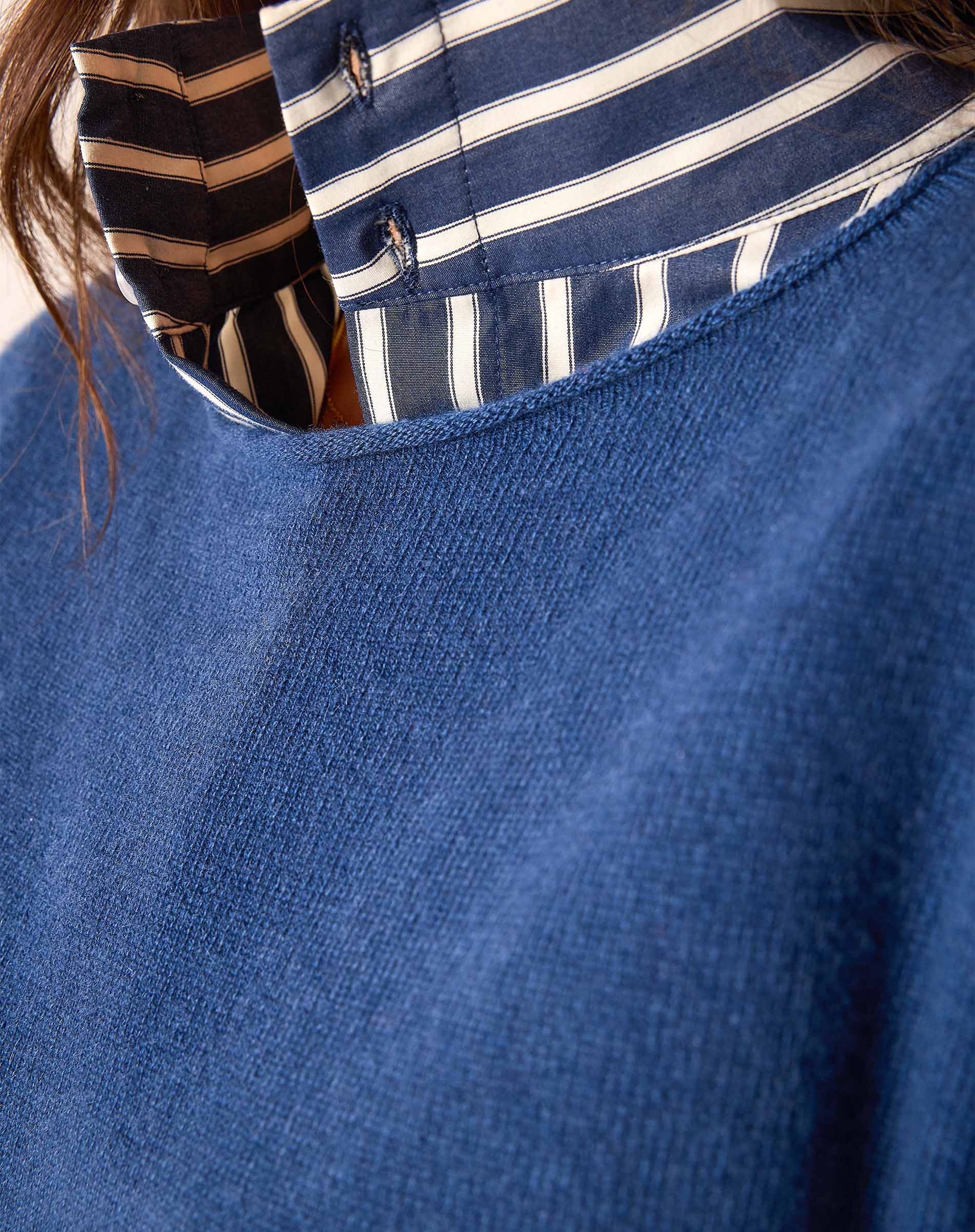 Yale Blue cashmere knit sweater featuring a cozy knit weave and layered over a blue and white striped button-down shirt.