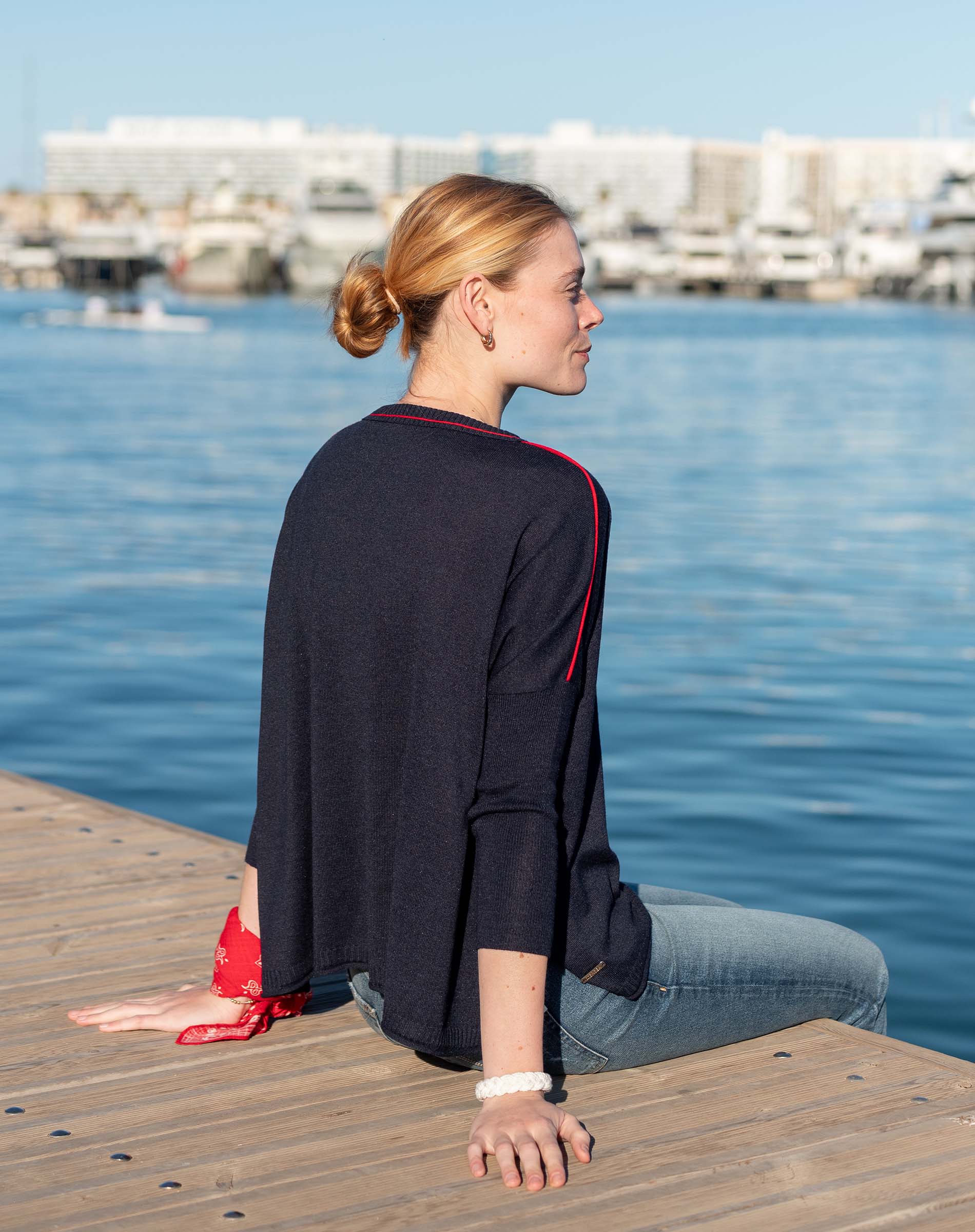Side view of the navy and red contrast crewneck knit top with 3/4 sleeves.