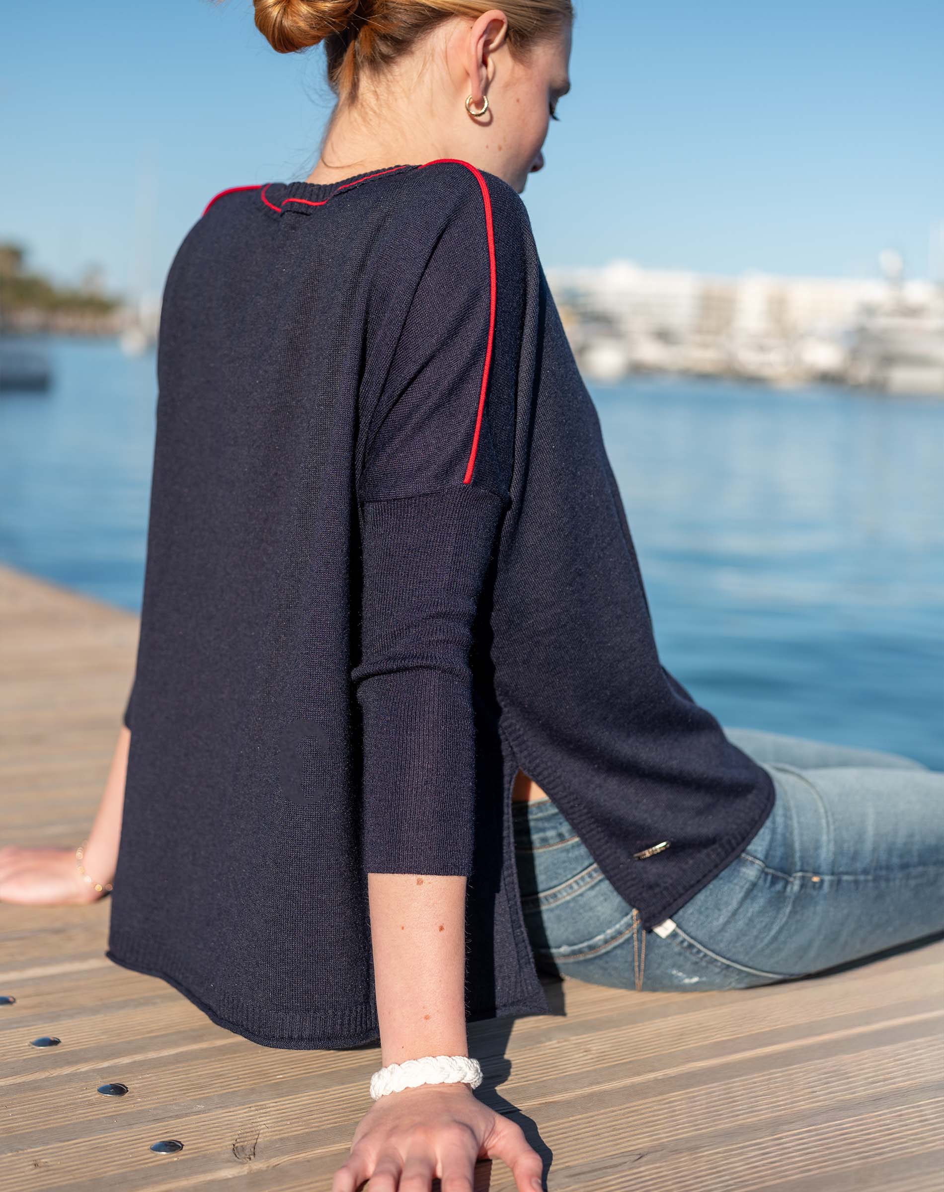Navy blue crewneck sweater with red contrast trim and wide sleeves.