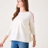 Woman wearing a cream sweater with red accents and blue jeans on a white background