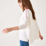 Woman wearing a white cardigan and blue jeans on a plain background