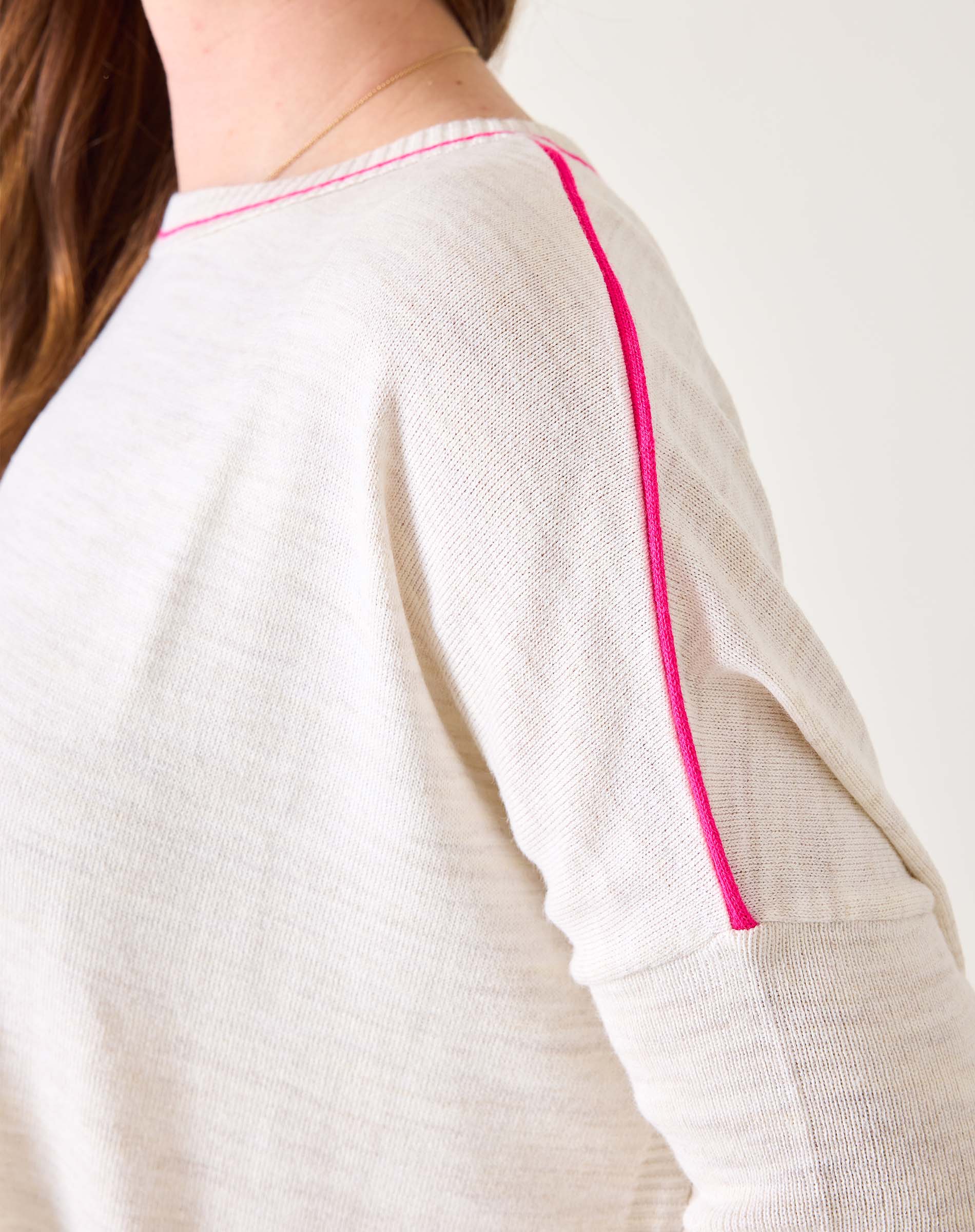 White garment with pink piping on a plain background