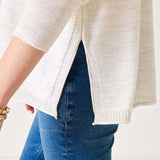 Person wearing a white sweater and blue jeans on a plain background
