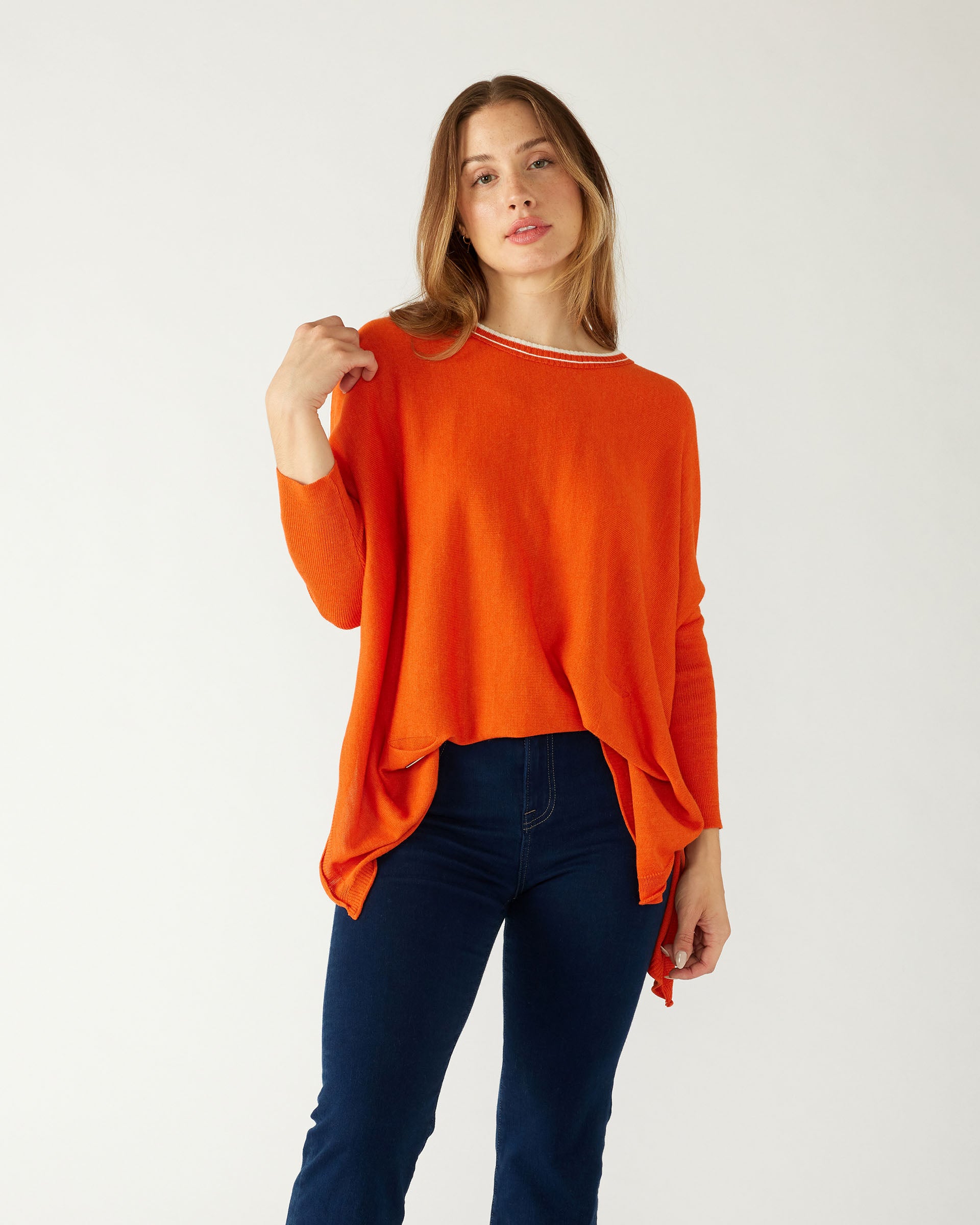 woman wearing mersea catalina contrast sweater in fresh clementine orange with white trim