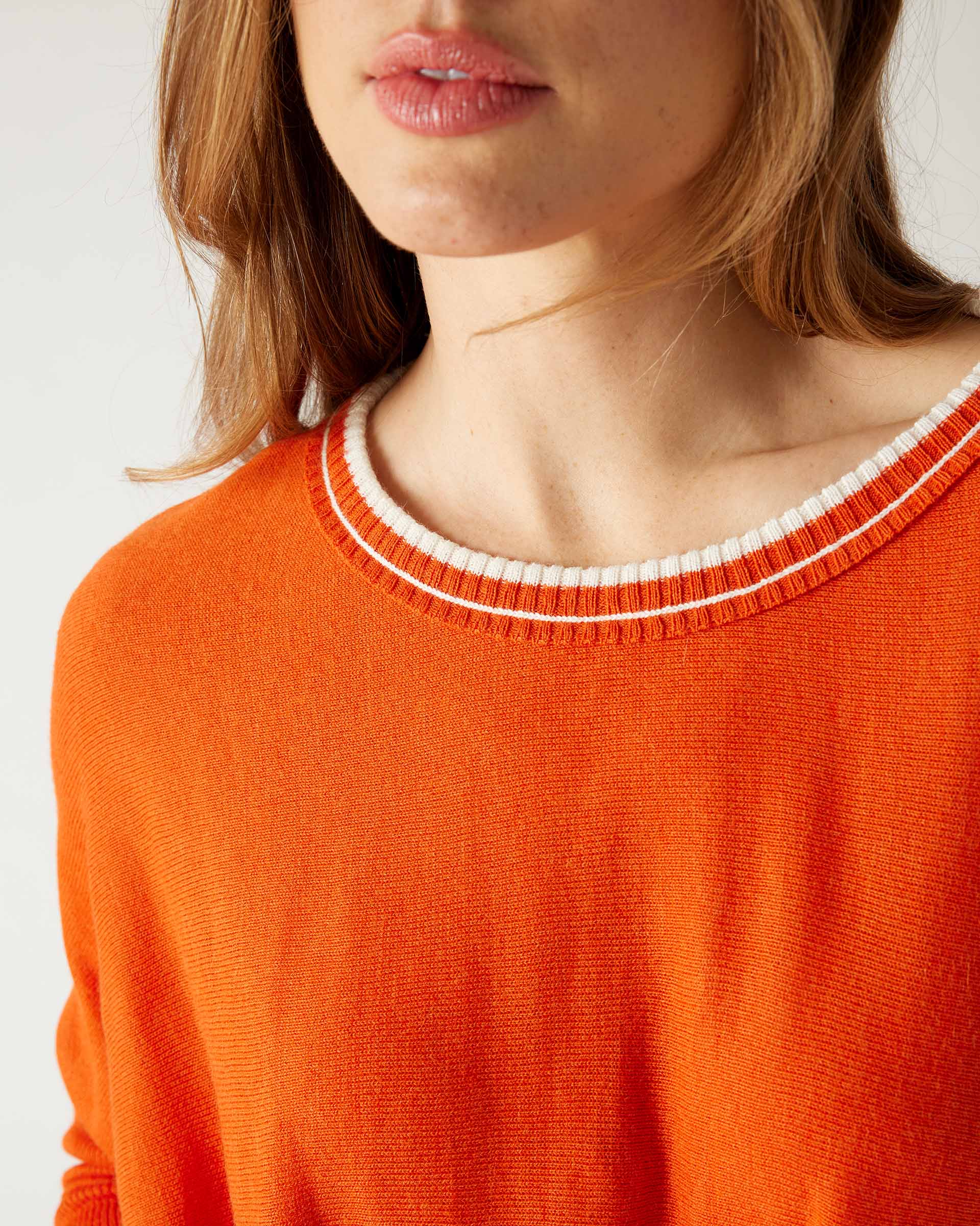 closeup of collar woman wearing mersea catalina contrast sweater in fresh clementine orange with white trim