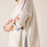 Person wearing a light-colored cardigan over a blue shirt with a neutral background