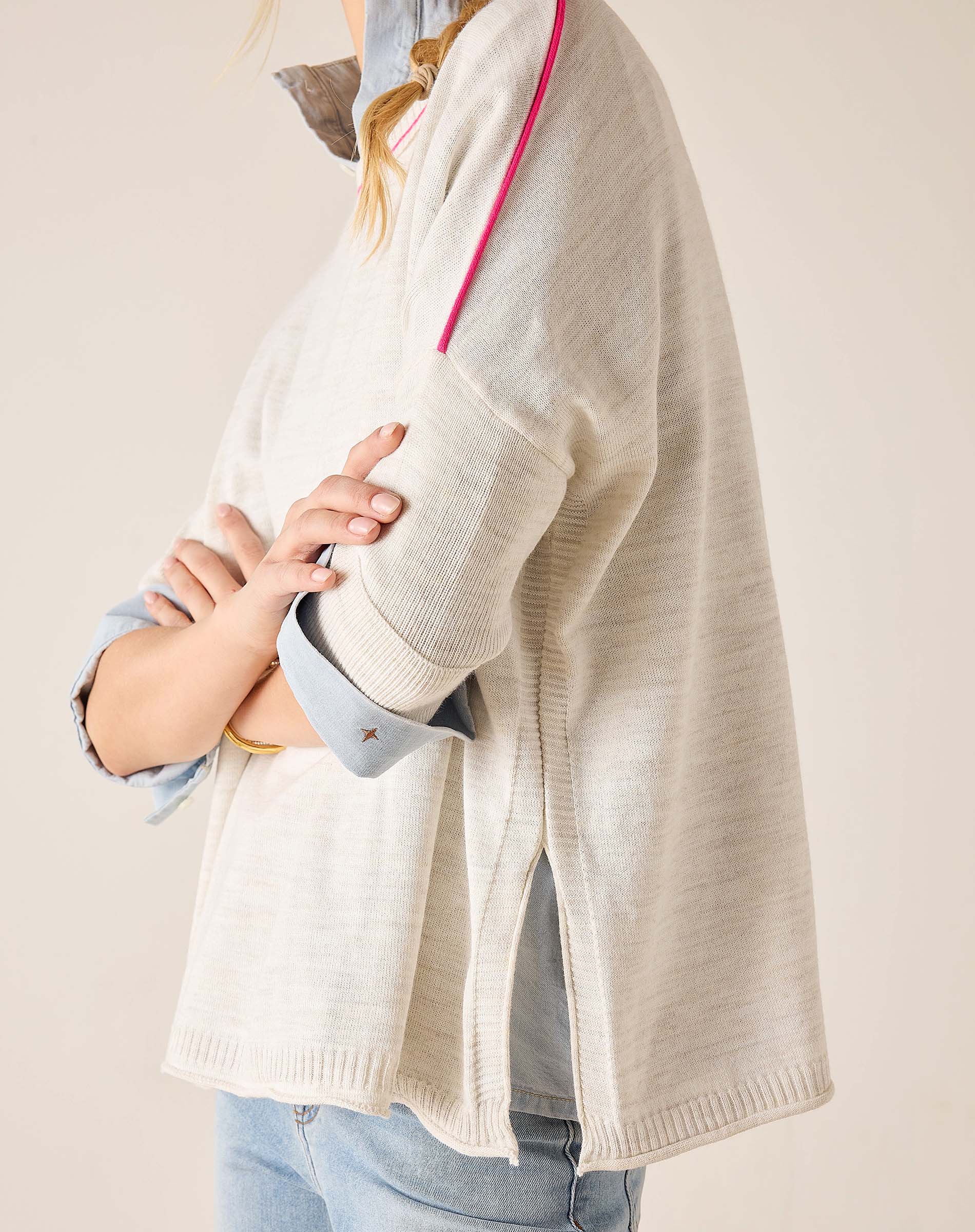 Person wearing a light-colored cardigan over a blue shirt with a neutral background