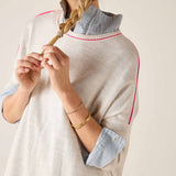 Woman wearing a light gray sweater with rolled-up sleeves and a braid, on a plain background