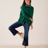 MERSEA ladies' travel-ready parakeet green cotton crewneck knit top paired with denim pants and sneakers.