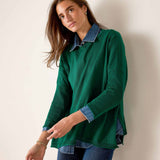 Parakeet green knit top layered over a denim button-down shirt and dark wash jeans.