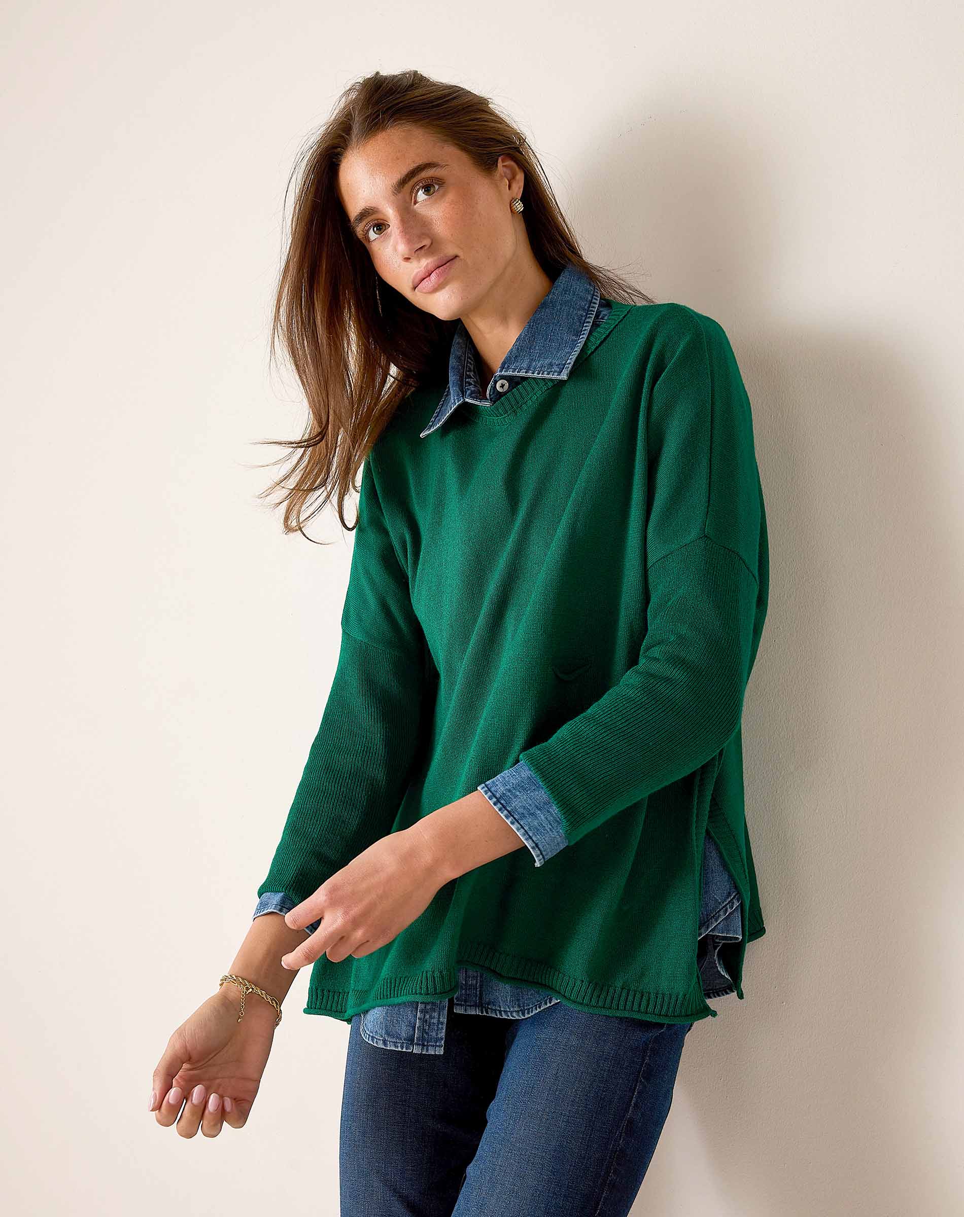 Parakeet green knit top layered over a denim button-down shirt and dark wash jeans.